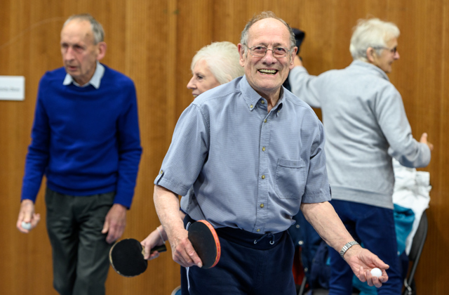 Older man smiling whilst playing table tennis