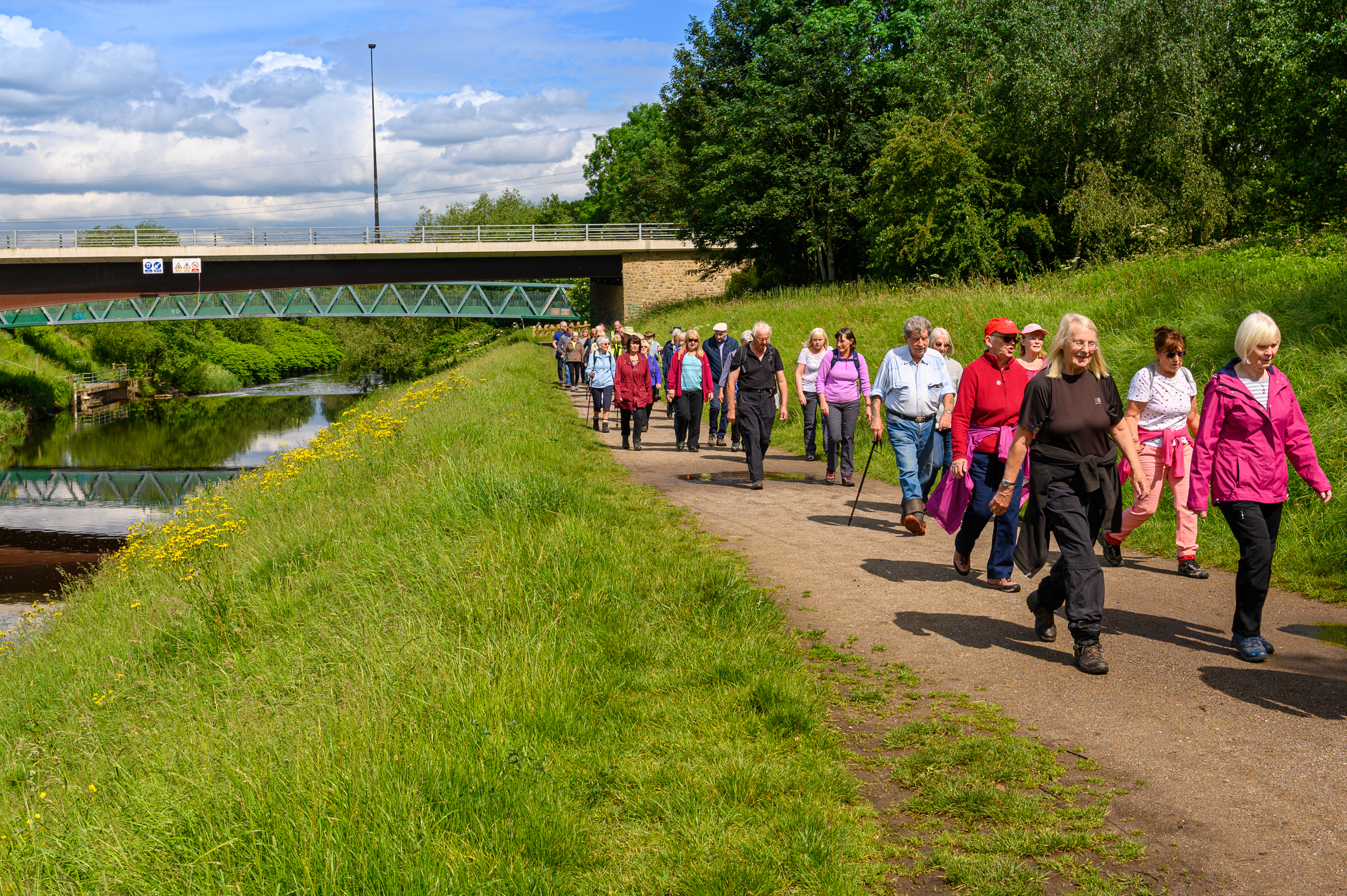 Large group walk along the bank of a river