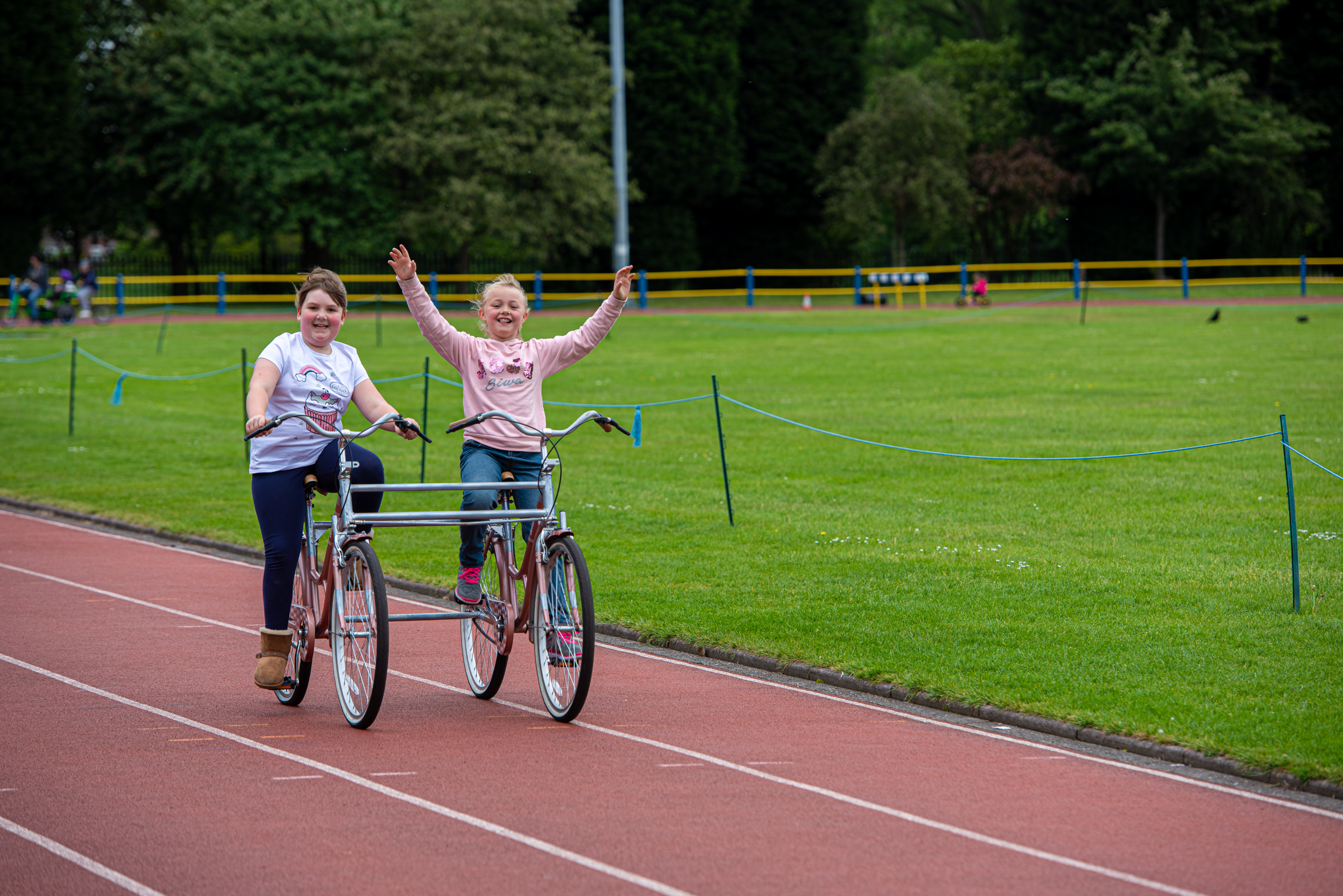 Two girls riding a tandem bike smiling