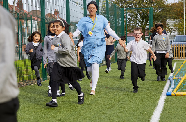 Teacher and schoolchildren running around taking part in The Daily Mile