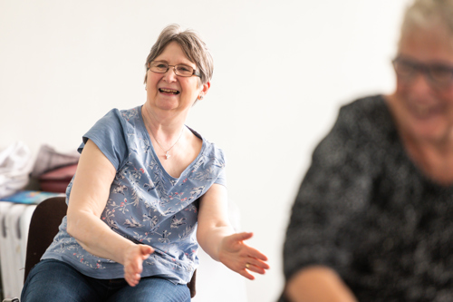 Lady sat in chair smiling whilst exercising