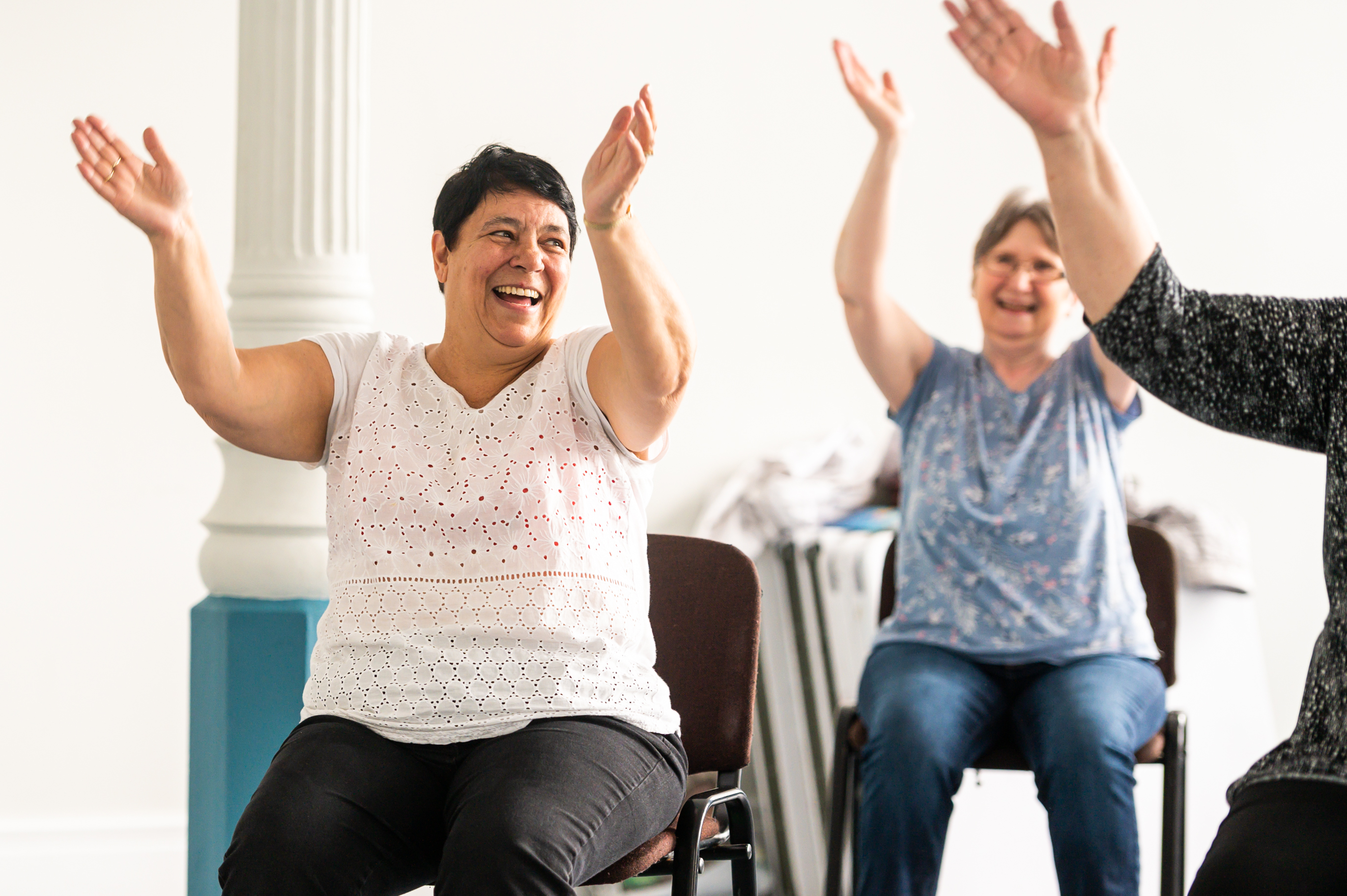 Two women smiling in a chair based exercise class