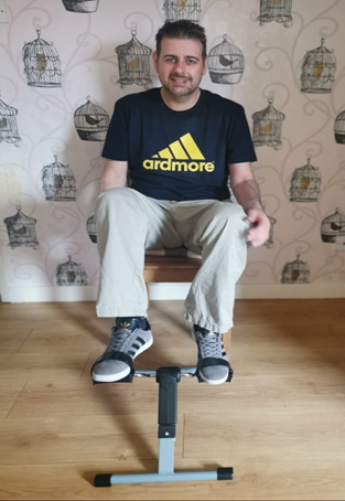 Stephen sat on a dining room chair whilst using a cycle pedal